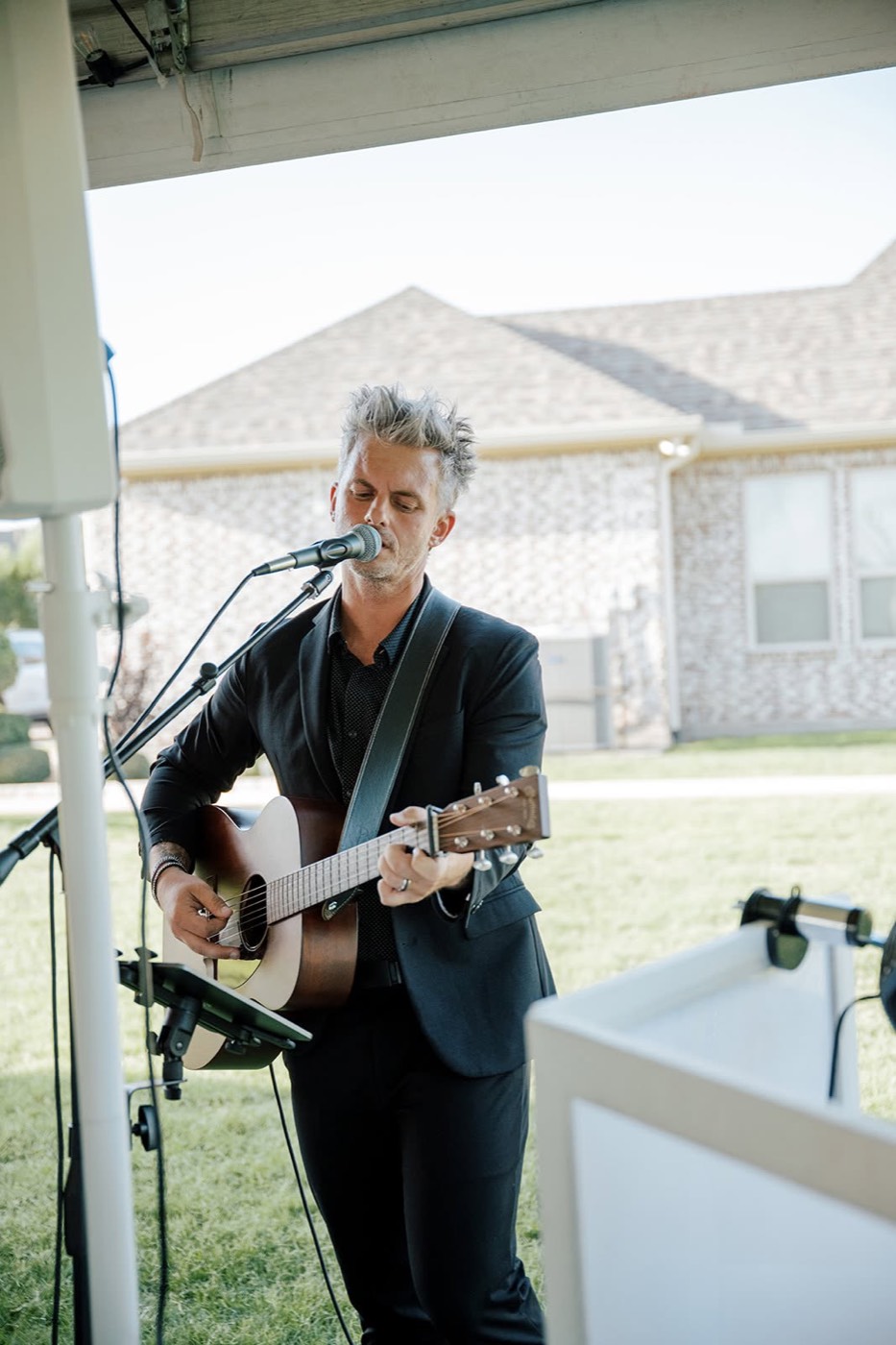 A live acoustic musician performing in a suit at a CM Promotions wedding